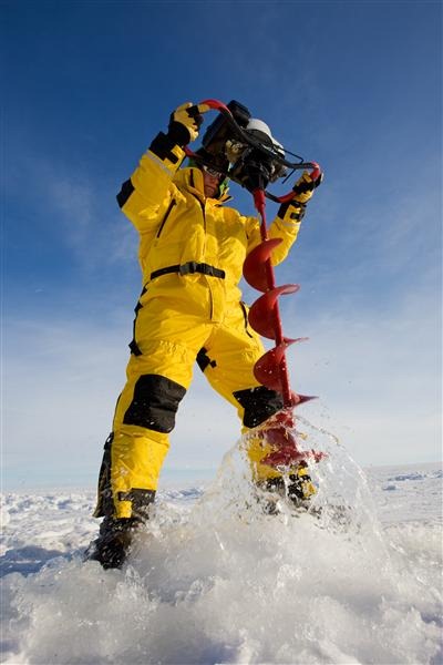 Ice fisherman drilling a hole with a power auger